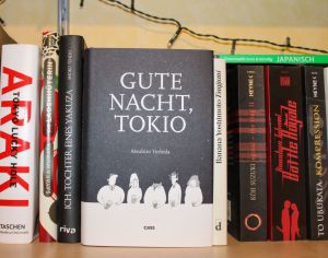 Cover der gebundenen Ausgabe von "Gute Nacht, Tokio" auf einem Bücherregal stehend.