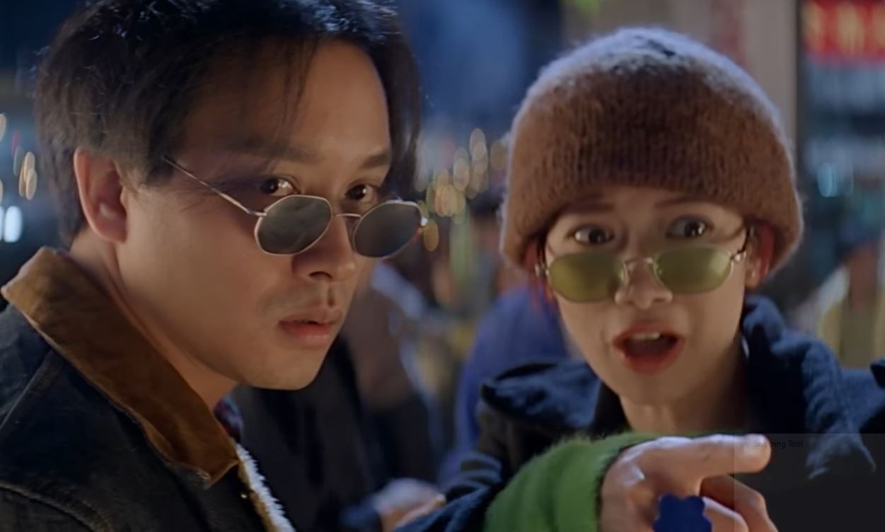 Leslie Cheung und Anita Yuen in einer Szene aus "Das Bankett des Kaisers", beide mit Sonnenbrillen auf der Nase, so dass die Augen darüber zu sehen sind.