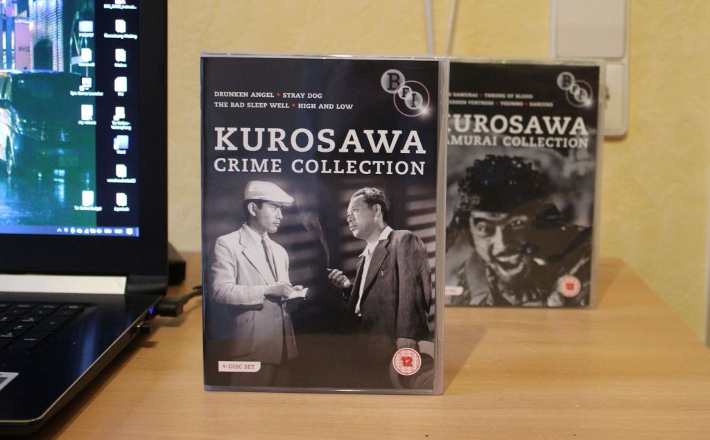 Aufrecht stehend auf einem Schreibtisch die DVD-Box "Kurosawa Crime Collection". Dahinter seine Samurai Collection.