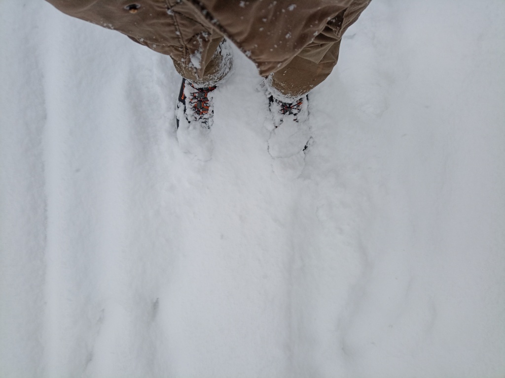 Meine Beine, die Schuhe darunter im Schnee eingesunken.