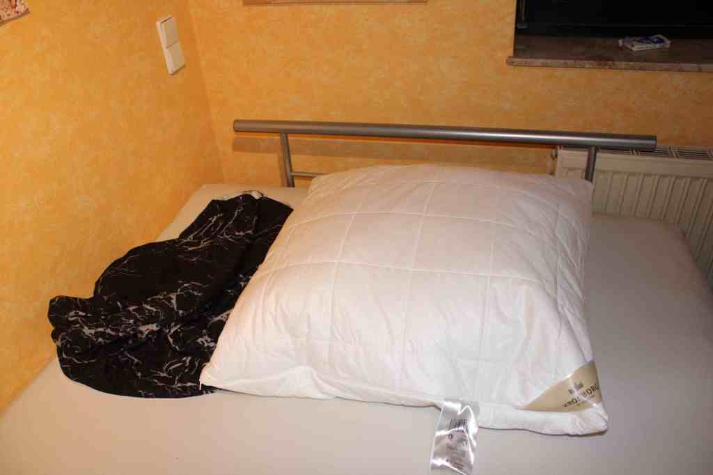 Ein weißes Kopfkissen auf einem Bett liegend, daneben der schwarze Bezug.