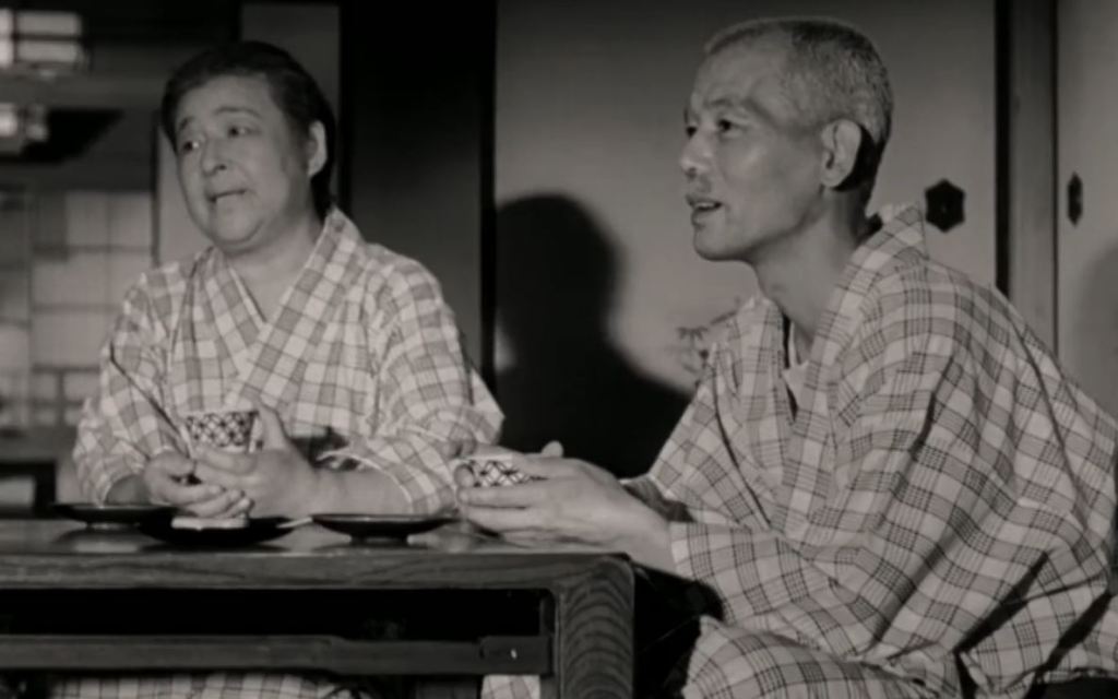 Das ältere Ehepaar aus "Reise nach Tokio" sitzt in Kimonos am niedrigen japanischen Tisch, in den Händen eine Tasse Tee und starrt versonnen jenseits der Kamera.