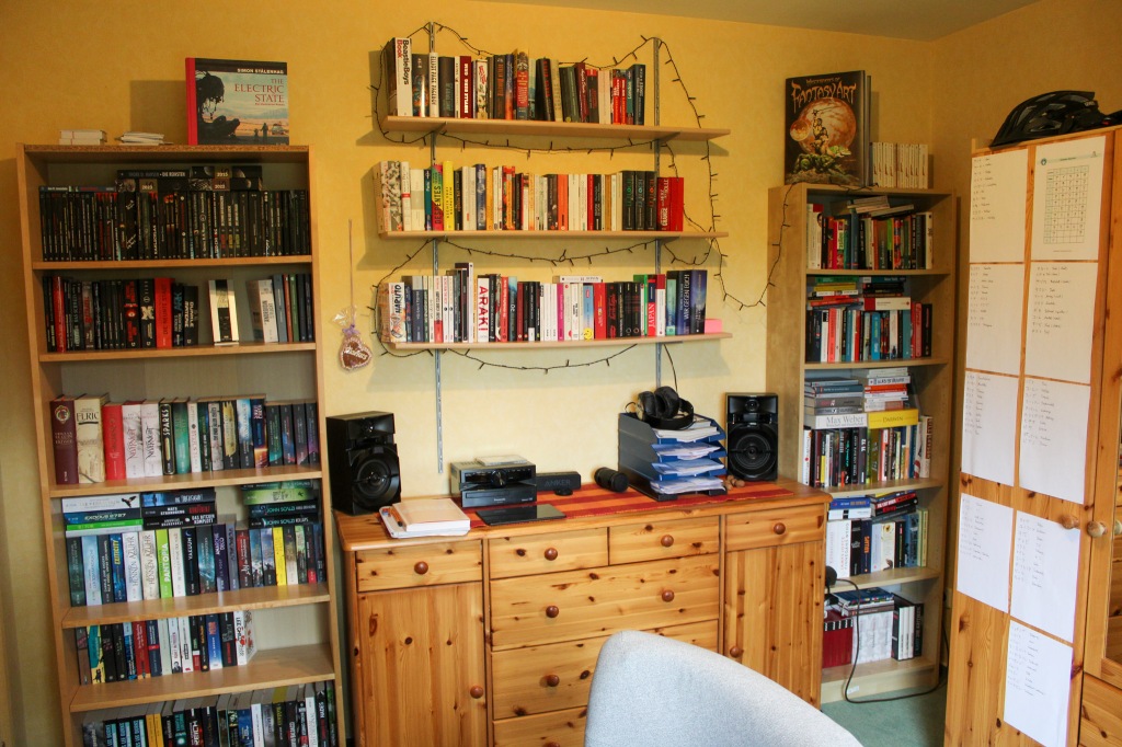 In der Mitte unten einen Kommode, darüber drei Reihen mit Bücherregalbrettern. Links und rechts der Kommode stehte jeweils ein Billy-Bücherregal von Ikea.
